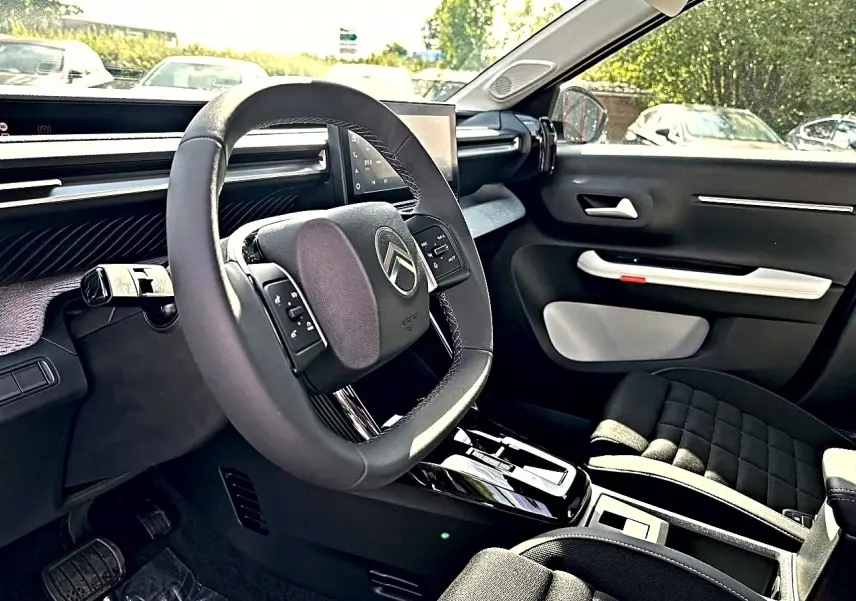Vue intérieure côté conducteur du Citroën C3 Aircross 2026, volant multifonction et sièges noirs avec console centrale.