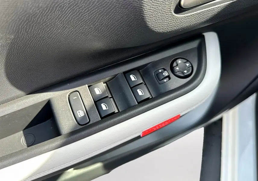 Gros plan sur la commande des vitres côté gauche de la porte avant d'une Citroën C3 Aircross blanche, avec bouton de réglage des rétroviseurs.