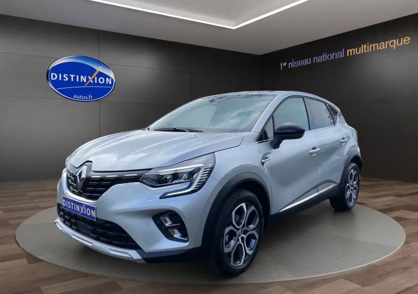 Renault Captur TCE 90 TECHNO gris Highland en 3/4 avant droit, avec jantes alliage et calandre noire brillante.