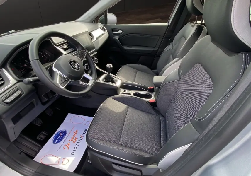 Vue intérieure côté conducteur du Renault Captur TCE 90 Techno 2024, sellerie tissu gris et console centrale avec boîte manuelle.