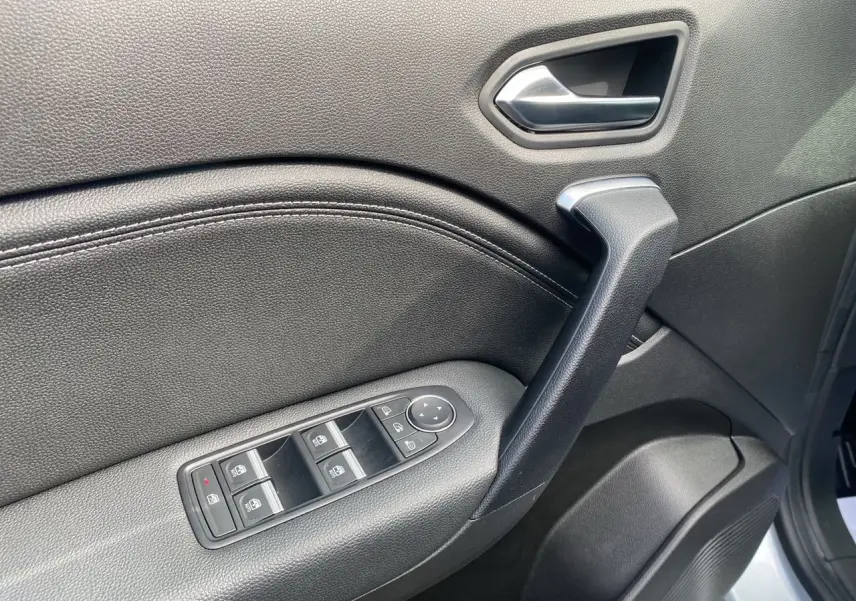 Gros plan sur la porte avant gauche intérieure noire du Renault Captur TCE 90 Techno 2024 avec commandes de vitres électriques.