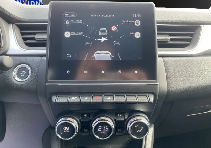 Tableau de bord du Renault Captur TCe 90 Techno 2024, écran tactile affichant aides à la conduite, ambiance intérieure noire.