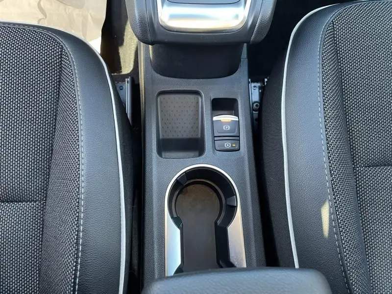 Vue plongeante sur la console centrale du Renault Captur gris métal 2022, avec porte-gobelet et frein à main électrique.
