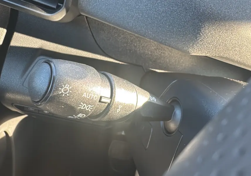 Gros plan sur la commande des feux et clignotants dans l’habitacle noir du Peugeot Rifter 2025.