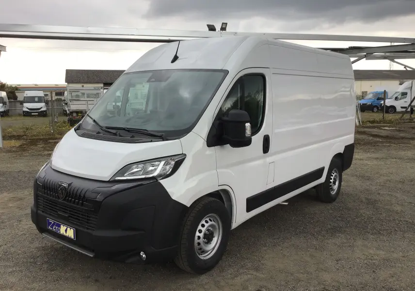 Fourgon Peugeot Boxer blanc vu en 3/4 avant droit, avec pare-chocs noir et jantes acier simples.