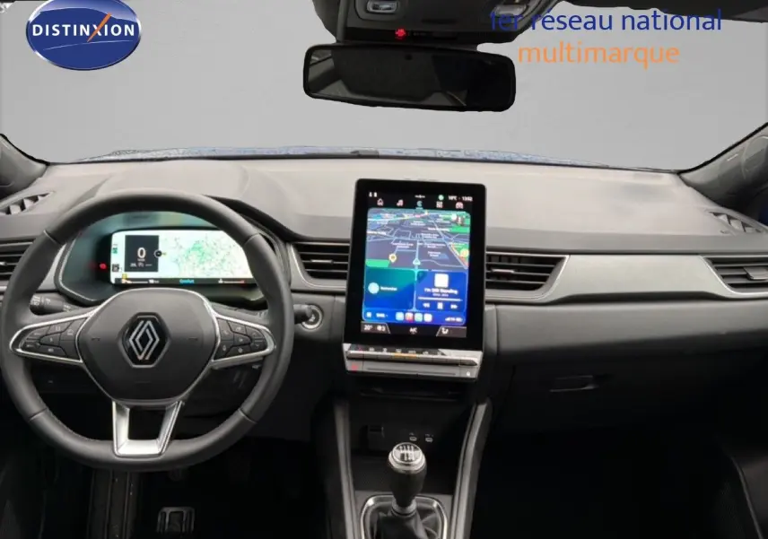 Vue intérieure avant du tableau de bord du Renault Captur bleu Iron Metal 2025 avec écran tactile vertical et volant multifonction.