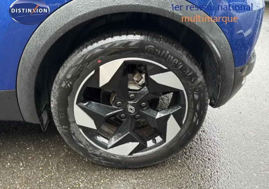 Gros plan sur la roue avant droite du Renault Captur bleu Iron Metal avec jante noire et argentée au design étoilé.