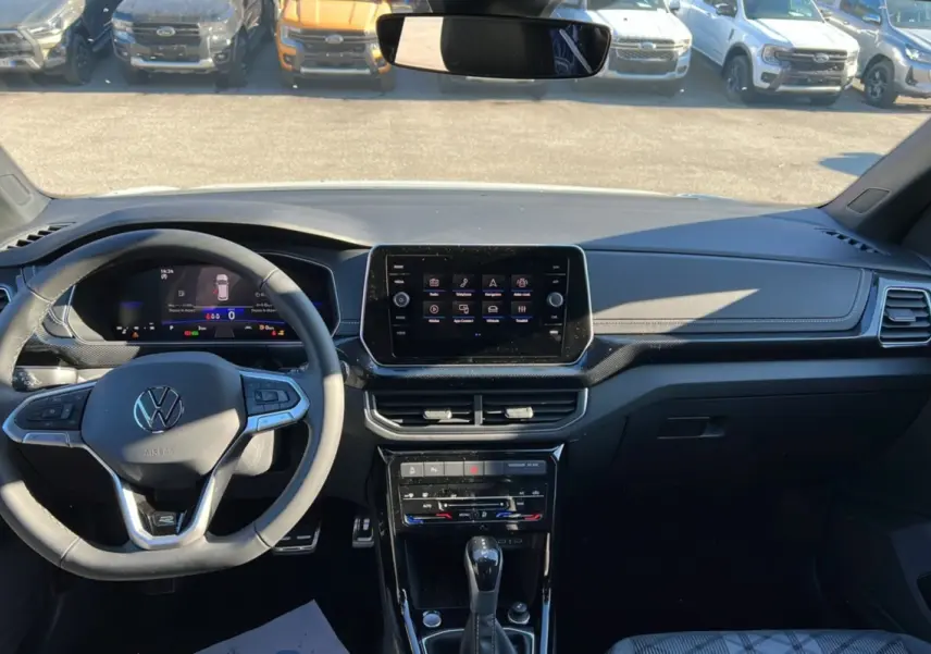 Vue intérieure avant du Volkswagen T-Cross blanc pur 2025, tableau de bord avec écran tactile et volant multifonctions cuir.