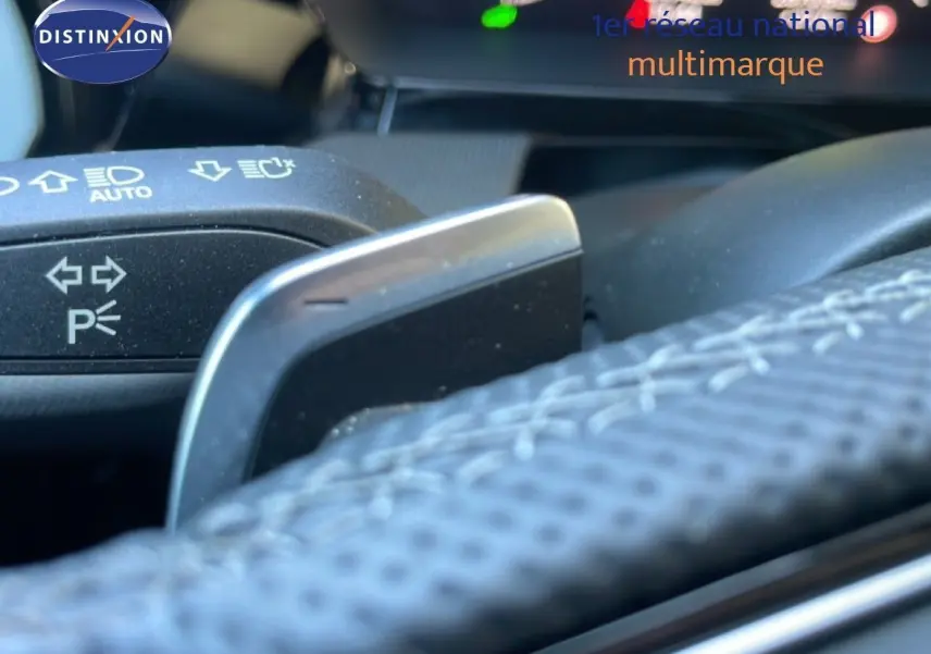 Gros plan sur la palette de changement de vitesse derrière le volant cuir perforé d’une Audi A3 Sportback noire hybride rechargeable.