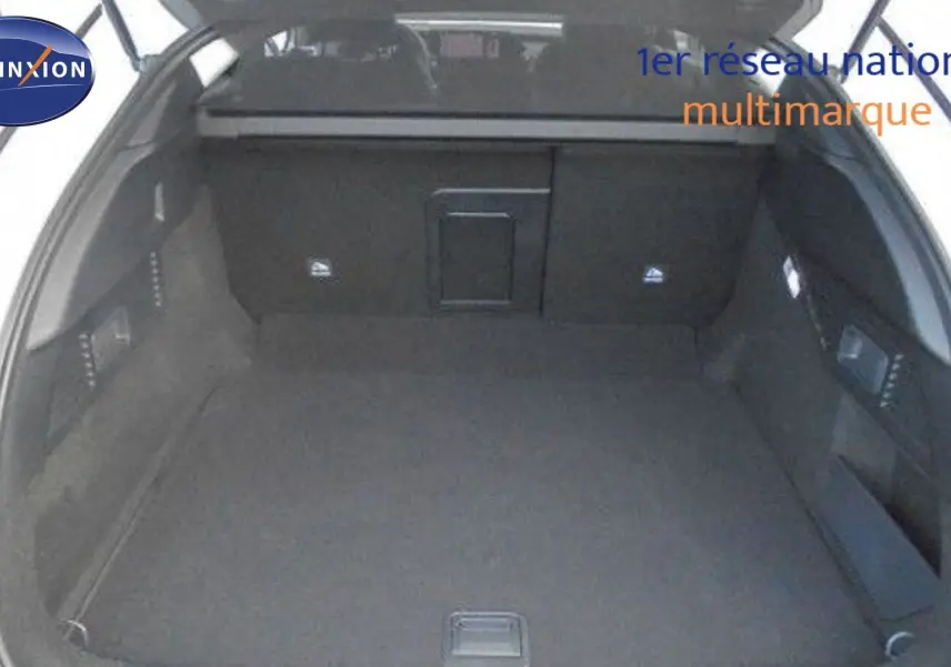 Coffre ouvert d'une Citroën C5 X blanc métal 2023, vue intérieure montrant un espace de chargement spacieux et noir.