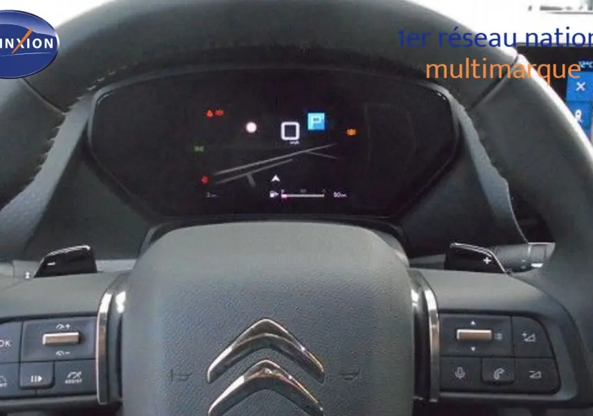 Vue rapprochée du volant cuir noir et du tableau de bord numérique d'une Citroën C5 X 2023.