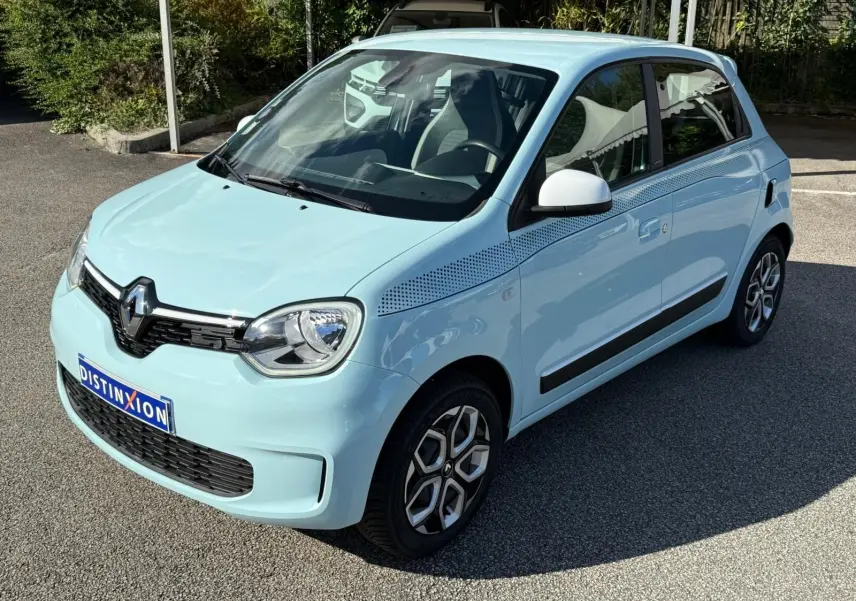 Renault Twingo III bleu dragée vue 3/4 avant droit avec jantes stylisées et bande décorative noire sur l'aile.