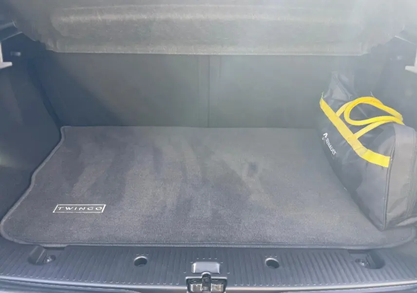 Coffre ouvert d'une Renault Twingo III bleu dragée, tapis de sol avec logo Twingo et sac d'accessoires Renault.
