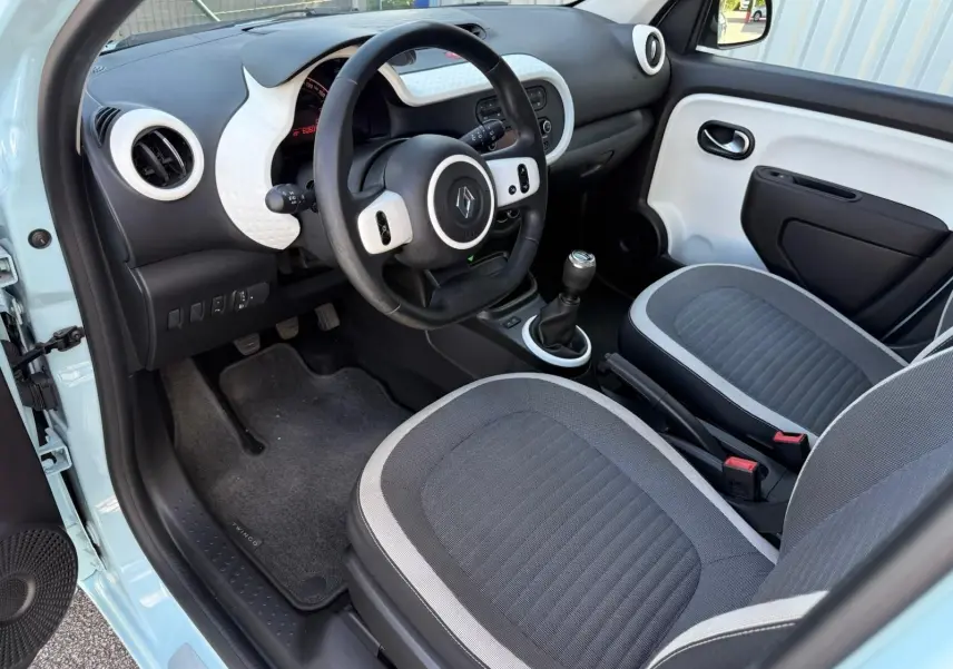 Vue intérieure côté conducteur de la Renault Twingo III bleu dragée, avec tableau de bord et sièges gris.
