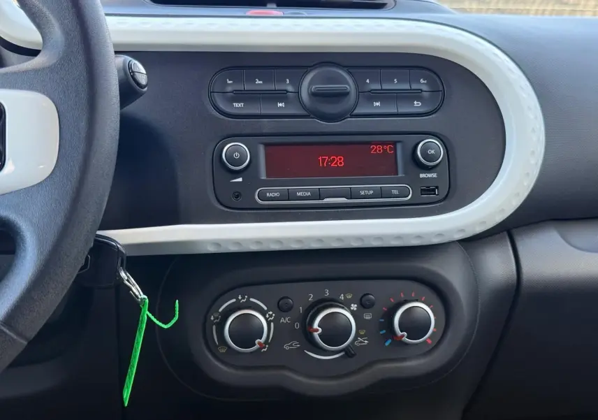 Vue rapprochée du tableau de bord de la Renault Twingo III bleu dragée, montrant la radio et les commandes de climatisation.