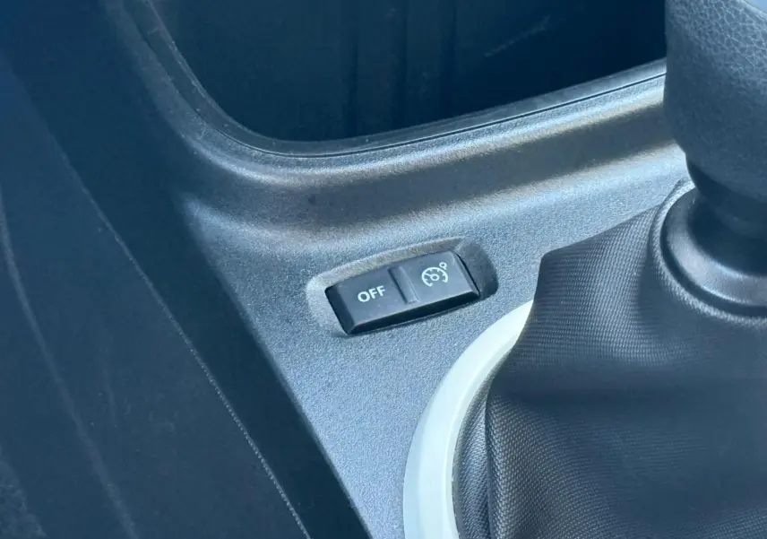 Gros plan sur le bouton de régulateur de vitesse désactivé à côté du levier de vitesses d'une Renault Twingo III bleu dragée.