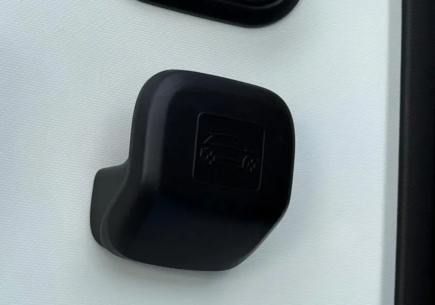 Gros plan sur la poignée intérieure de porte noire d'une Renault Twingo III bleu dragée, mettant en valeur le pictogramme voiture embossé.