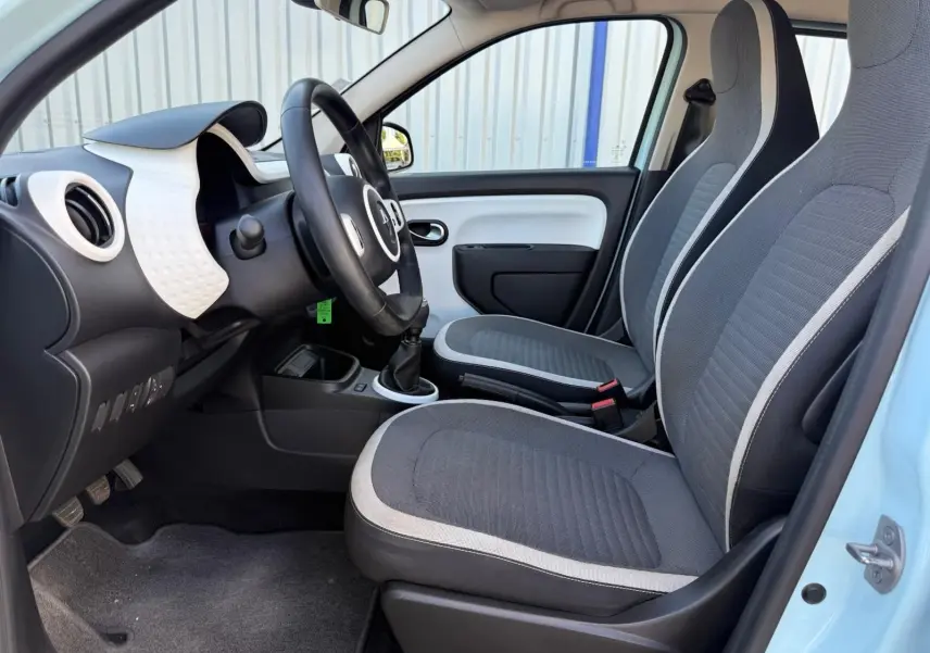 Intérieur avant droit de la Renault Twingo III bleu dragée 2021 avec sièges tissu gris et volant noir.
