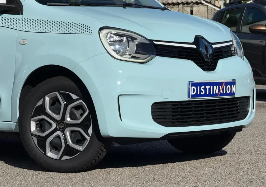 Vue 3/4 avant gauche d'une Renault Twingo III bleu dragée avec jantes au design géométrique et calandre noire.