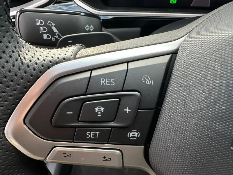Gros plan sur les commandes du régulateur de vitesse au volant perforé du Volkswagen T-Roc 2025 finition R-Line noir Grenadilla.