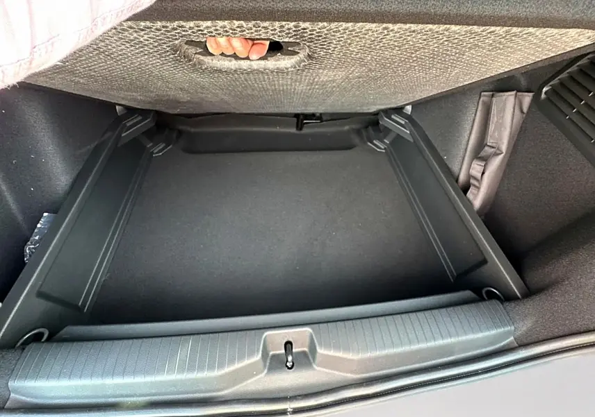 Vue plongeante sur le coffre noir vide du Citroën C3 Aircross 2026, montrant le plancher de coffre mobile et la poignée intégrée.