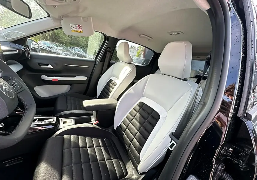 Vue intérieure côté conducteur de la Citroën C3 Aircross noire 2026, sièges bicolores noir et blanc avec accoudoir central.