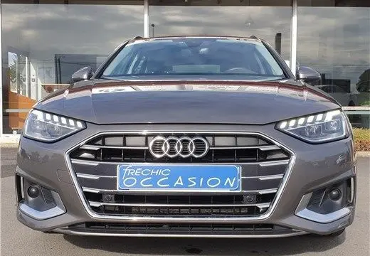 Vue frontale d'une Audi A4 Avant Business gris terra de 2020 avec calandre hexagonale et phares LED allumés.