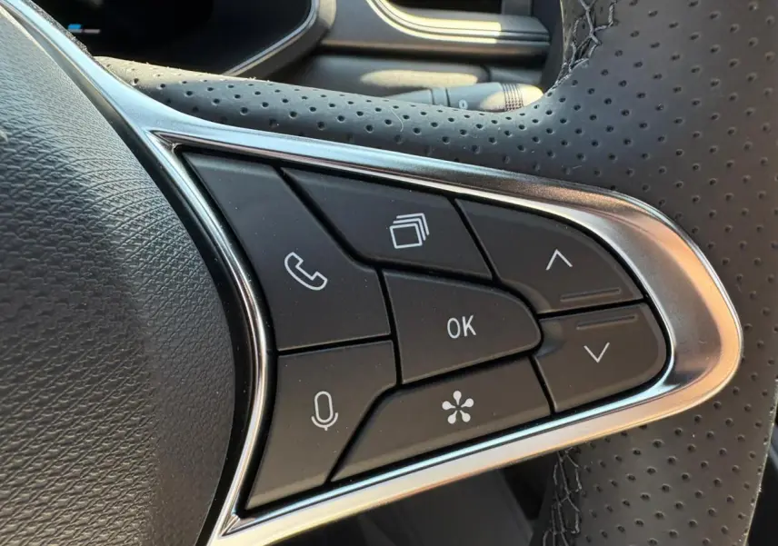 Gros plan sur les commandes multifonctions noires du volant perforé de la Renault Symbioz blanc nacré 2025.