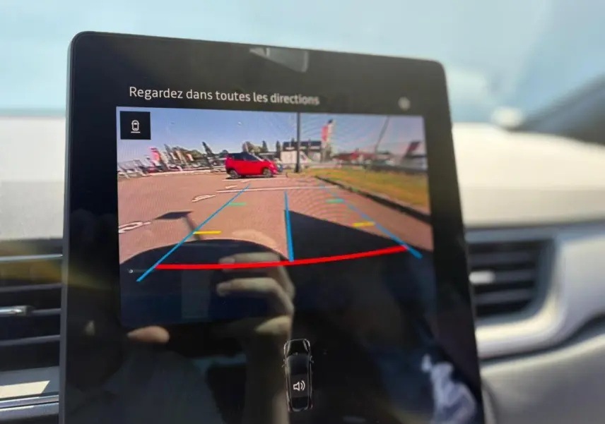 Écran de caméra de recul dans Renault Symbioz blanc nacré, vue intérieure avec indications de stationnement colorées.