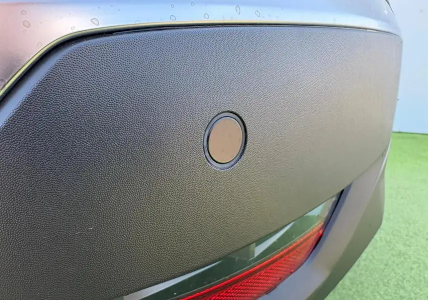 Gros plan sur le capteur de stationnement arrière intégré dans le pare-chocs noir du Renault Symbioz blanc nacré.