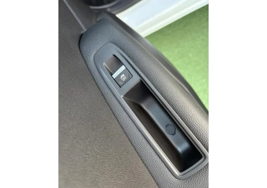 Gros plan sur le bouton de lève-vitre électrique côté gauche d'une Renault Symbioz blanc nacré avec intérieur noir.