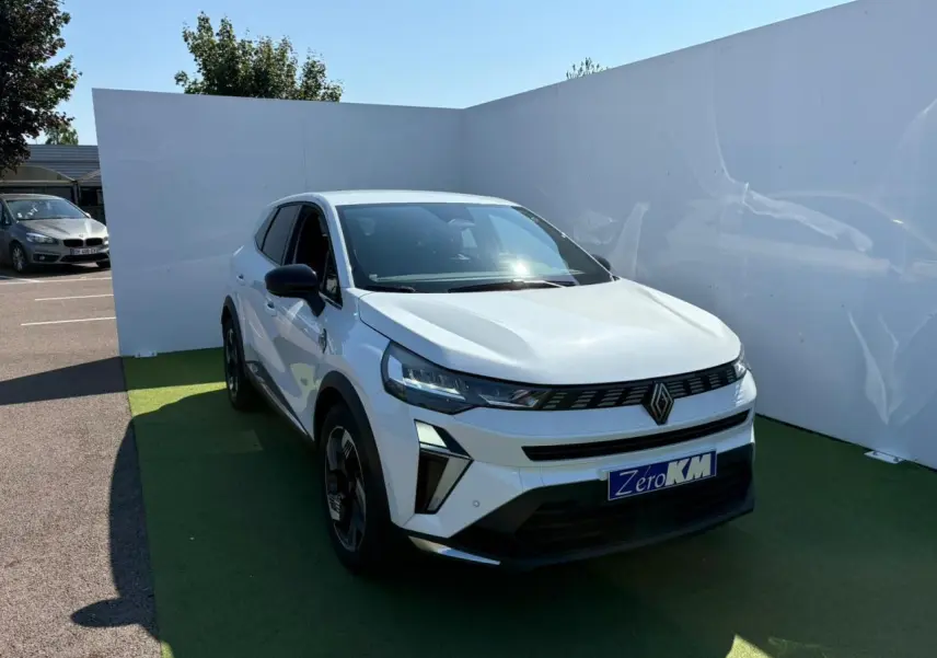 Renault Symbioz blanc nacré vu de 3/4 avant droit, calandre noire avec logo Renault centré et jantes 18 pouces noires.