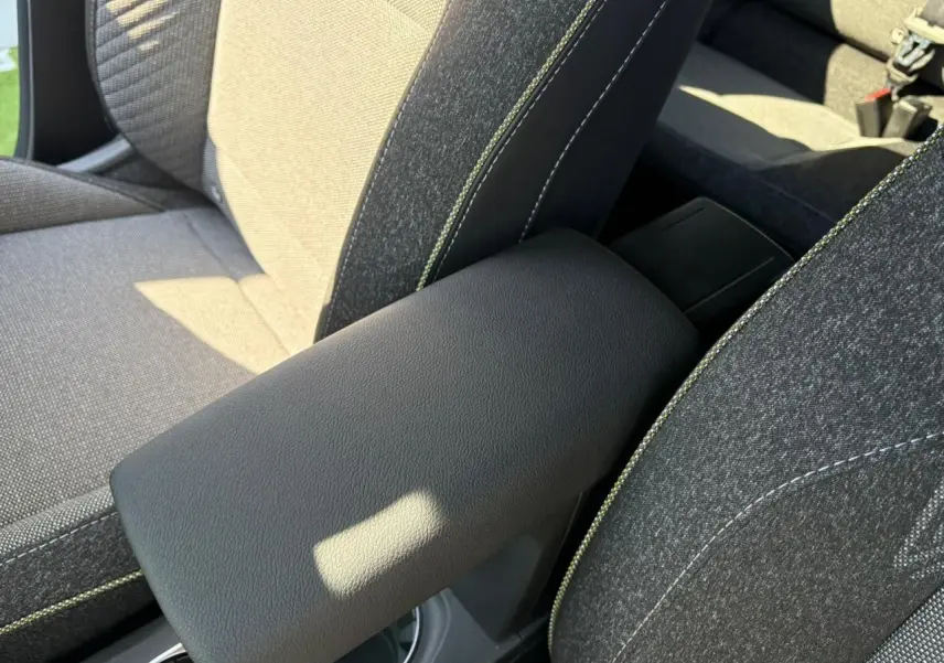 Accoudoir central noir entre les sièges avant gris avec surpiqûres vertes d'une Renault Symbioz 2025.