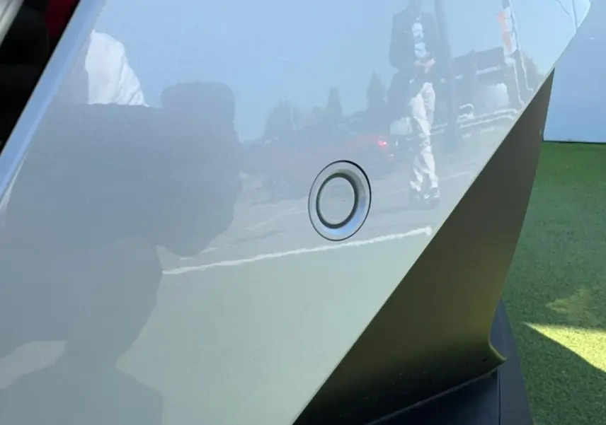 Gros plan sur un capteur de stationnement arrière du Renault Symbioz blanc nacré, reflétant l'environnement extérieur.