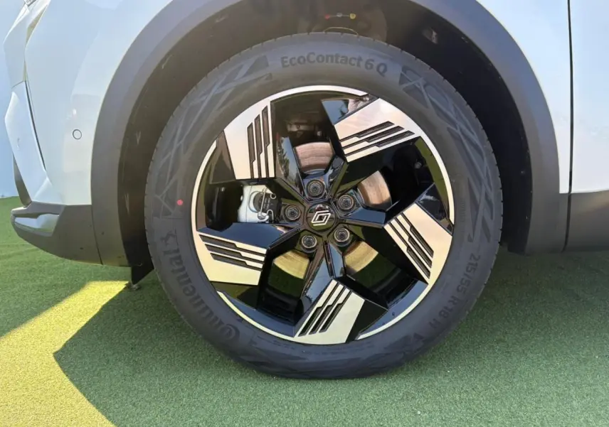 Gros plan sur la jante 18 pouces noire et argentée du côté droit du Renault Symbioz blanc nacré, avec pneu Continental.