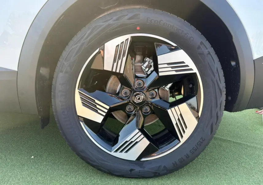 Gros plan sur la jante 18 pouces bicolore noire et argentée du Renault Symbioz blanc nacré, avec pneu Continental.