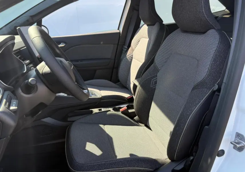 Vue intérieure côté gauche de la Renault Symbioz 2025 blanc nacré, sièges tissu gris avec volant et console centrale visibles.