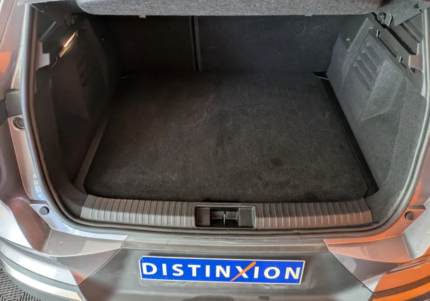 Coffre ouvert vu de dessus sur Renault Symbioz gris cassiopée métal, montrant l’espace de chargement vide et tapis noir.