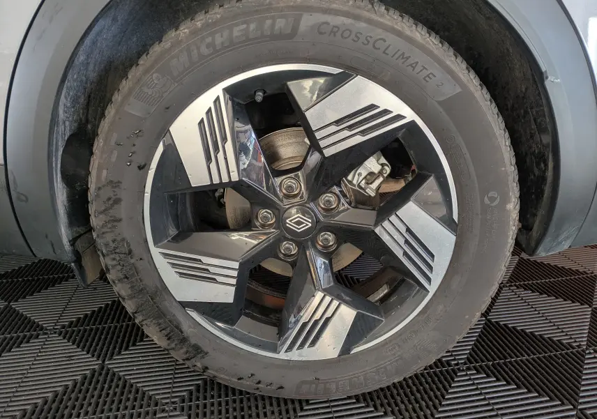 Gros plan sur la roue avant gauche du Renault Symbioz gris Cassiopée, jante alliage bicolore au design géométrique.