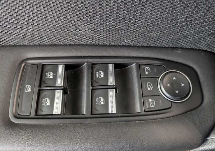 Gros plan sur les commandes de lève-vitres et rétroviseurs électriques noires de la Renault Symbioz gris cassiopée.