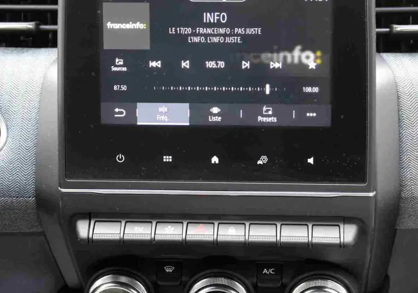 Vue rapprochée de l'écran tactile central et des commandes de climatisation du Renault Clio 2025 en intérieur gris-noir.