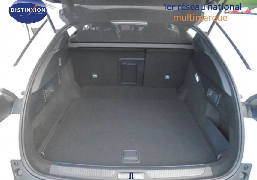 Coffre ouvert d'une Citroën C5 X blanc métal, vue arrière montrant l'espace de chargement vide et les finitions intérieures noires.