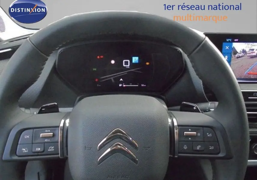 Volant en cuir noir de Citroën C5 X 2023 avec commandes intégrées et tableau de bord numérique en arrière-plan.