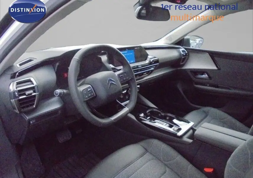 Vue intérieure côté conducteur de la Citroën C5 X 2023 avec tableau de bord moderne et sièges tissu gris foncé.