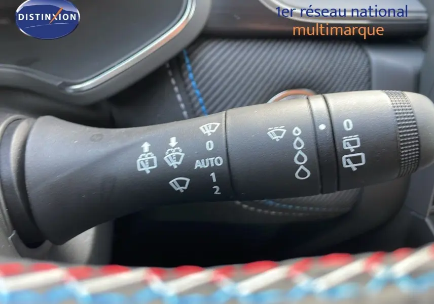 Gros plan sur la commande d'essuie-glace du Renault Captur E-Tech noir étoile avec détails blancs et coutures bleues sur le tableau de bord.