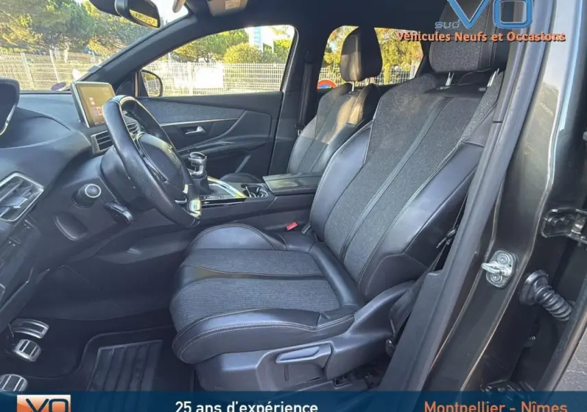 Intérieur avant droit du Peugeot 3008 gris foncé 2018, sièges cuir et tissu, volant cuir et console centrale visible.