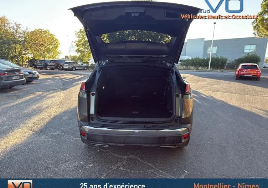 Vue arrière d’un Peugeot 3008 gris foncé 2018 avec coffre ouvert, stationné en extérieur sur parking.