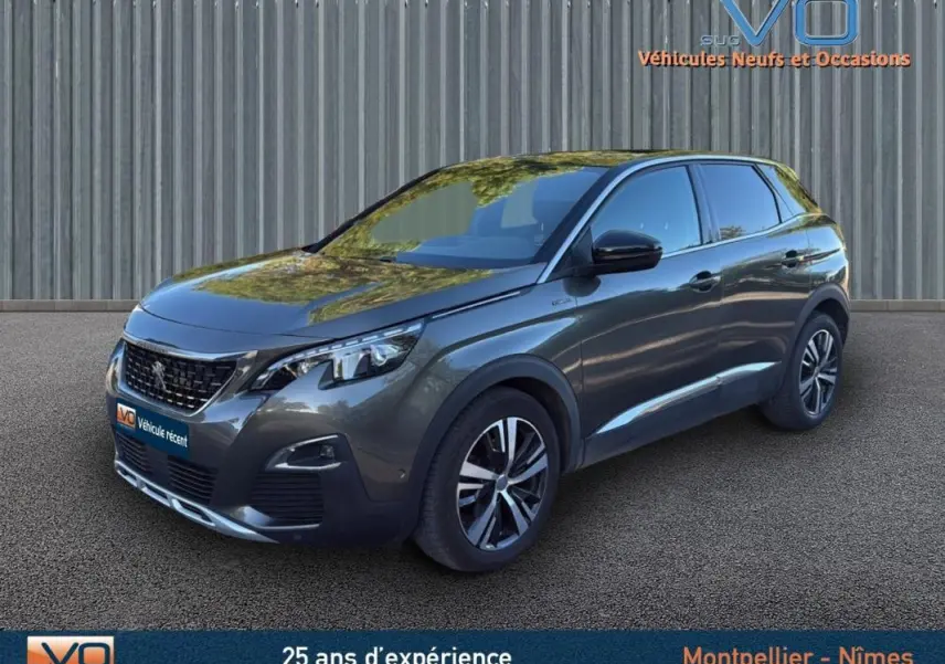 Peugeot 3008 gris foncé en 3/4 avant droit, avec jantes alliage 18 pouces et phares LED visibles.