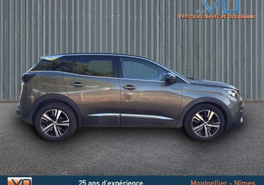 Profil côté droit du Peugeot 3008 gris foncé de 2018 avec jantes alliage 18 pouces, garé devant un mur métallique.