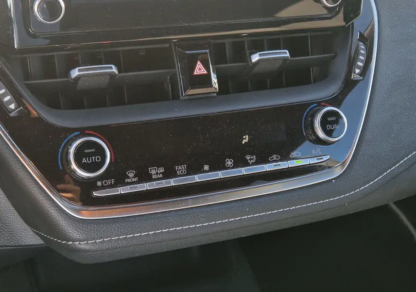 Vue rapprochée de la console centrale noire de la Toyota Corolla Hybride 122h Design, avec commandes climatisation et boutons lumineux.